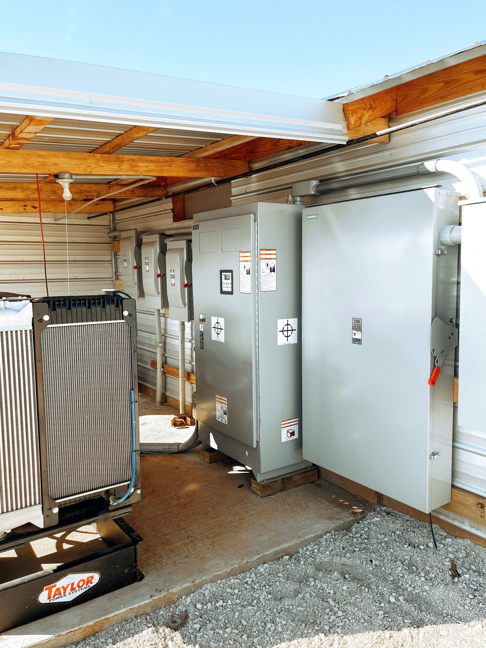 Standby generator and transfer switch cabinets installed under a covered pad